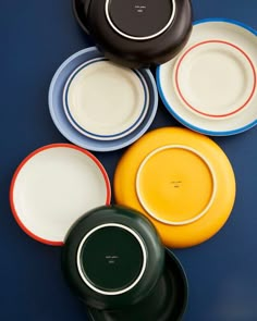 four different colored plates sitting next to each other on a blue table top with white and black trim