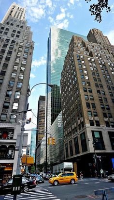 an intersection in the city with tall buildings and cars driving down it's street