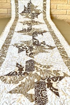 a quilted table runner is on display in front of a brick wall and floor