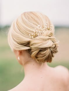 an instagram photo of a blonde woman with her hair in a low bun and pearls