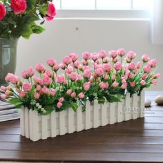 pink flowers are arranged in white vases on a table next to books and rocks