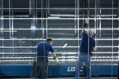 two men in blue shirts are working on a large metal structure that is being constructed