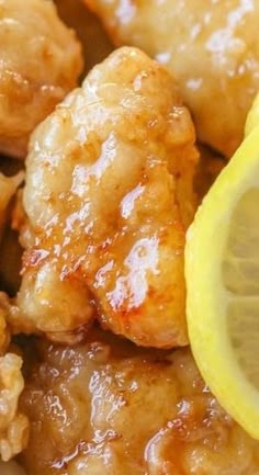 a close up of some food with lemon wedges on the side and chicken wings