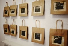 there are many pictures hanging on the wall with paper bags around them that hold photos