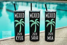 three black tumblers with green palm trees on them next to a swimming pool in mexico