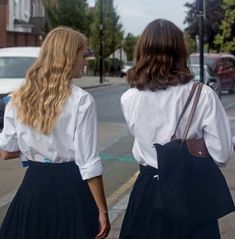 two women walking down the street in skirts