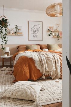 a bedroom with white walls and wooden flooring, an orange blanket on the bed