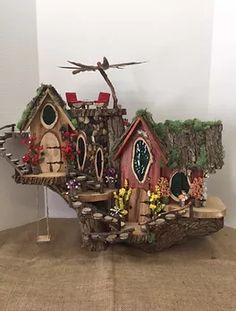 a small house made out of wood with plants and flowers on the roof is shown in front of a white wall