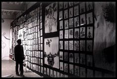 a man standing next to a wall covered in pictures