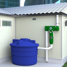 a large blue barrel sitting next to a white building with a green pipe on the side