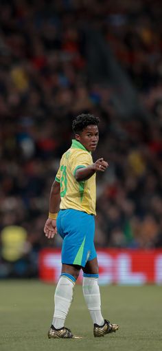 a soccer player in yellow and blue uniform standing on the field with his hand out