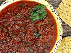 a bowl filled with chili and tortilla chips on top of a wooden table