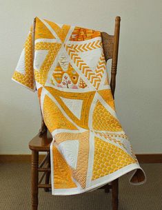 an orange and white quilt on a wooden chair