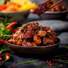 a bowl full of food with chopsticks sticking out of the meat in it