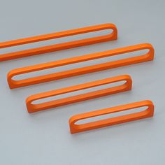 four orange plastic handles on a white surface