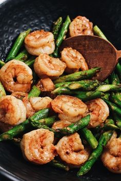 asparagus and shrimp in a skillet with a wooden spoon