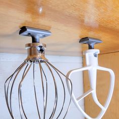 two kitchen appliances are hanging from the ceiling and one has a wire whisk attached to it