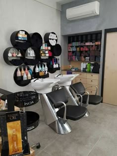 a hair salon with chairs and shelves full of products on the wall behind it,