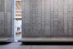 two concrete benches sitting next to each other in front of a wall with an open door