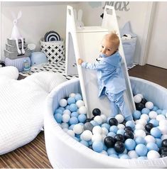 a baby in a blue suit climbing into a ball pit