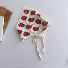 a crocheted hat with strawberries on it next to a book