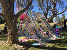 a group of people standing around a tree with balloons and streamers hanging from it