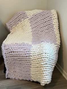 a crocheted blanket sitting on top of a wooden floor next to a wall