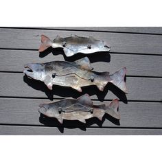 three metal fish sculptures sitting on top of a wooden floor