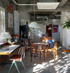 a room filled with lots of wooden chairs and table next to a plant in a pot