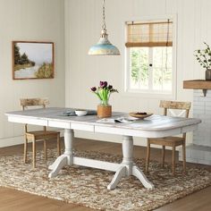 a dining room table with two chairs and a potted plant