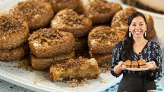 a woman is holding a plate full of baked goods