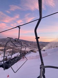 a ski lift going up the side of a snow covered mountain at sunset or dawn