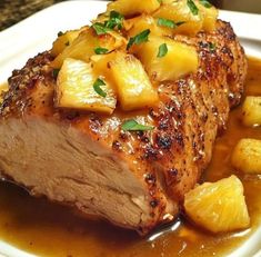 a white plate topped with meat covered in pineapple sauce and garnished with parsley