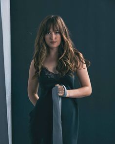 a woman in black dress holding a gray tie