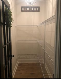 an empty pantry with shelves and lights on the ceiling, in front of a sign that reads grocery