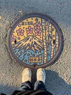 a man standing in front of a colorfully painted manhole cover