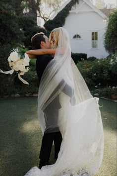 a bride and groom kissing in front of a house