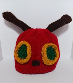 a red knitted hat with two green eyes and brown antlers on the front