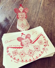 two envelopes with christmas designs on them sitting on a wooden table next to an ornament