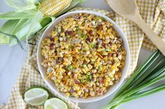 a white bowl filled with corn next to green onions