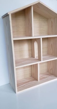 a wooden shelf with several shelves on it and one section missing from the top, in front of a white wall