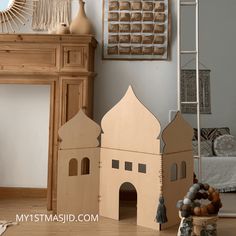 a cardboard model of a house next to a fireplace