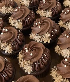 chocolate cupcakes with frosting and sprinkles are arranged on a table