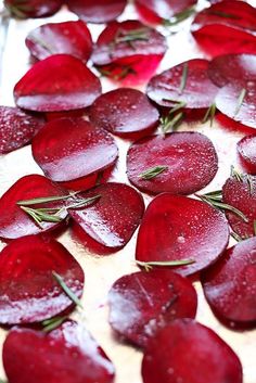 sliced beets on a cutting board with water droplets and rosemary sprinkles