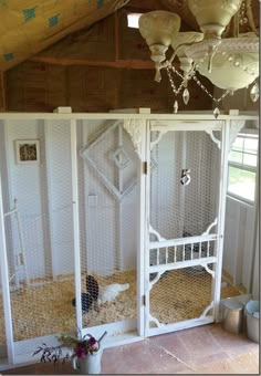 a large white chicken cage in the corner of a room filled with hay and eggs