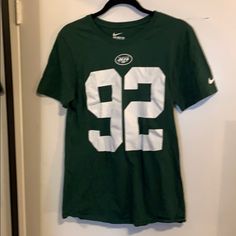 a green and white football jersey hanging on a wall