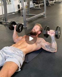 a man laying on the ground with two dumbbells in front of his chest