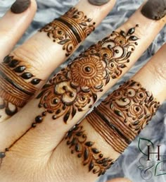 two hands with henna tattoos on them, one is showing off the intricate design