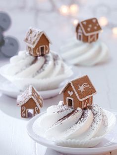 some cupcakes with icing and gingerbread houses are on a white plate