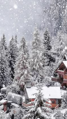 a snowy scene with houses and trees in the foreground, snow falling on the ground